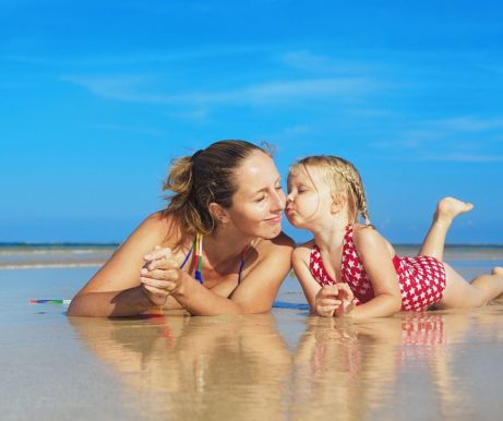 Maminka s tříletou dcerkou leží v písku na plážil